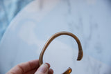 The open C-shape and smooth, aged patina of the copper cuff bracelet.