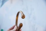 Profile view of the antique copper alloy snake cuff showing its imperfect, open shape.