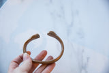 An antique copper alloy bracelet with an open cuff design and worn patina.