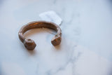 The sculpted form and rich patina of an antique African copper snake cuff.