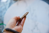 Hand holding the vintage African bronze fish, revealing its handmade textured body and light patina.