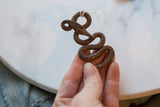 Vintage African metal snake held in hand, showing its textured, aged patina.