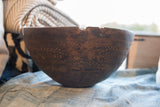 Aged rim of the antique African wooden bowl, showing imperfections and carved geometric patterns.