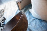 Dark, aged wood texture with a distinct chip on the antique African bowl's rim.