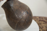 Vintage African wooden pitcher, close-up of dark aged surface with visible cracks and repairs.