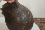 Vintage African wooden pitcher surface with visible cracks and aged texture.