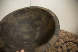 A close view of the aged interior and carved rim of the vintage black wooden bowl.