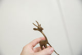 Hand holding vintage African bronze fawn, highlighting its sculpted head and textured antlers.