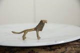 Side profile of a vintage African bronze lion showing its slender form and textured mane.