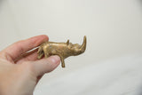 Vintage bronze rhino held in hand to show its collectible size and aged golden patina.