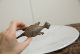 A hand holding the vintage bronze lizard to show its scale and mottled surface.