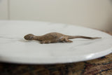 Side profile of a handmade bronze lizard showing its aged, rustic texture.