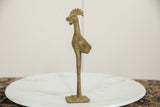 Vintage African bronze bird figurine in profile, highlighting its aged texture and tall legs.