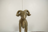 The powerful, expressive face and large, curved horns of the vintage African bronze ram.