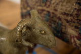 Detailed view of a vintage bronze ram's head, showing aged patina and a curved horn.