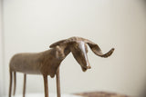 Angled profile of a vintage African bronze ram's textured head and curved horns.