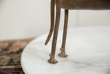 Close-up of the vintage African bronze ram's slender, textured legs and feet.