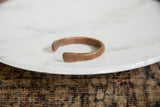 The distinctive flattened ends and the aged, oxidized patina of the African copper bracelet.