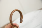 Close-up showing the hand-formed curve and rich patina of the antique copper bracelet.