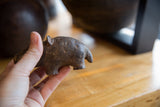 Small vintage African bronze hippo held to show its scale and handmade texture.
