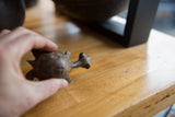 Hand holding vintage African bronze turtle, revealing handmade texture and rich patina.