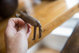 The small, textured vintage bronze warthog held to show its scale.