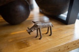 Vintage bronze warthog collectible with a rustic patina displayed on a wooden shelf.