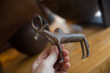 A hand holding the vintage bronze zebu sculpture, showing its scale and rustic patina.