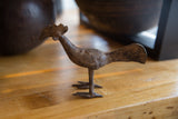 Profile view of a handmade African bronze bird with a long tail and textured patina.