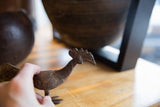 A hand holding the vintage African bronze bird, showing its scale and handmade texture.