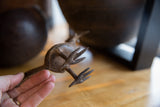 Detailed view of the cast bronze feet and rustic texture on a vintage African bird sculpture.