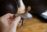 Vintage African bronze bird held in hand, highlighting its textured body and tail.