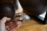 Hand-held view of vintage African bronze bird's three-pronged feet, showing unique handmade texture.
