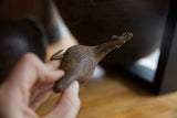 Hand holding vintage African bronze bird, featuring its ribbed texture.