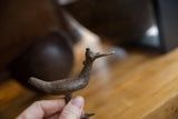 A vintage African bronze bird sculpture held to show its handmade texture and scale.