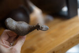Side profile of a handmade bronze bird showing its flat bill and rustic texture.