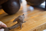 Handmade African bronze standing fish, showing textured head and spiral eye detail.