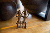 Close-up of textured vintage African bronze figures' stylized heads and raised arms.