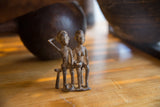 Vintage African bronze sitting figures, highlighting textured surfaces and handmade details.