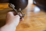 Vintage African bronze people sitting figure held in hand, showcasing aged texture.