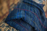 Close-up of vintage African indigo textile, revealing distinct hand-woven blue, pink, and gold stripes.