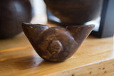 Aged, hand-carved surface of an antique wooden African ceremonial cup showing its central raised detail.