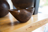 Angled profile of an antique African wooden cup showing its hand-carved geometric pattern.