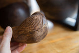 Hand-carved crosshatch detail on the antique African cup's aged wooden surface.
