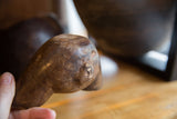 Close-up of the antique wooden cup's hand-carved character and smooth, aged surface.