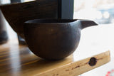 Side view of the vintage African wooden pitcher highlighting its spout and carved rim.