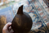 Angled view of the vintage African wooden pitcher's dark, hand-carved body and spout.