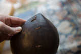 Close-up of historic wire repairs on the dark, aged wood of the pitcher.