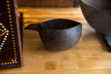 Hand-carved trim and rustic staple repairs on the vintage African wooden pitcher.