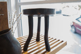 Detail of vintage African wooden stool's dark wood top, highlighting aged cracks.